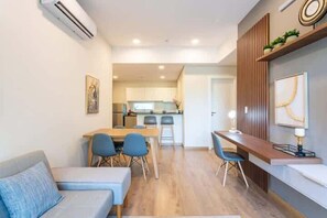 Ein modernes Wohnzimmer mit Sofa, Esstisch, Stühlen und einer Küche im Hintergrund.