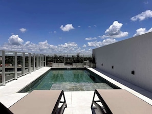 Ein Pool auf dem Dach mit blauem Himmel und Gebäuden in der Ferne.