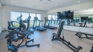 Ett gym med löpband, styrketräningsmaskiner och en tv-skärm.