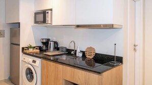 A modern kitchen with built-in appliances, a microwave, a washing machine, and a toaster. - Modern Studio with Pool, Gym & Balcony in Asunción (Asunción)