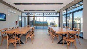 Uma sala de reuniões ampla, com uma longa mesa de madeira e cadeiras, grandes janelas com vista para a cidade e um design de teto moderno.
