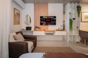 Ett modernt vardagsrum med en soffa, ett soffbord, en tv som är monterad på väggen och en bokhylla.