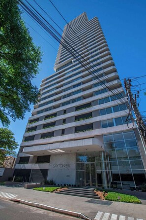 Een hoog, modern gebouw met een glazen entree en een bord waarop 'SKY TOWER' staat.