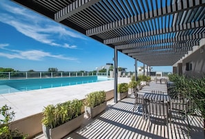 A rooftop pool area with a pergola, outdoor seating, and potted plants. - Executive Retreat w/ Balcony | Sauna & Pool (Asunción)
