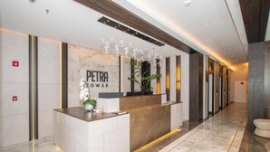 A reception desk with a marble countertop, a potted plant, and a sign that reads 'PETRA POWER'. - Urban High-floor One BR Escape, Petra Tower (Asunción)