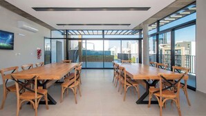 Ein geräumiger Konferenzraum mit langem Holztisch und Stühlen, großen Fenstern mit Stadtblick und einem modernen Deckenstil.