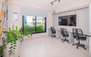 Een moderne kantoorruimte met een groot raam, een flatscreen televisie en verschillende bureaustoelen.
