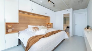 Un dormitorio moderno con cabecera de madera, ropa de cama blanca y lámparas de noche.