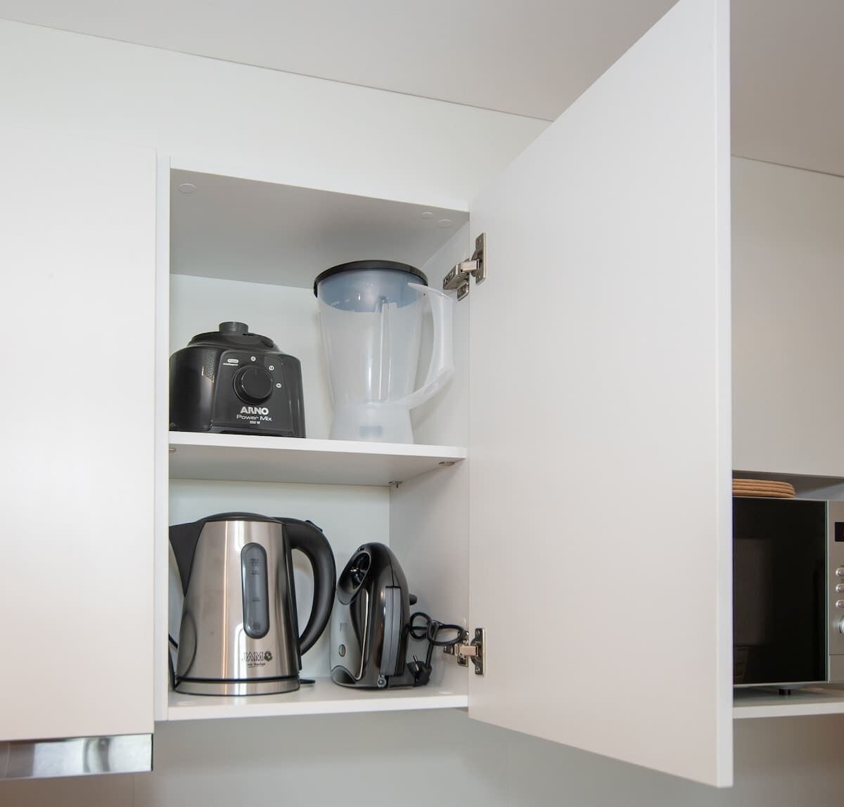 A kitchen with a blender, kettle, and coffee maker on open shelves.