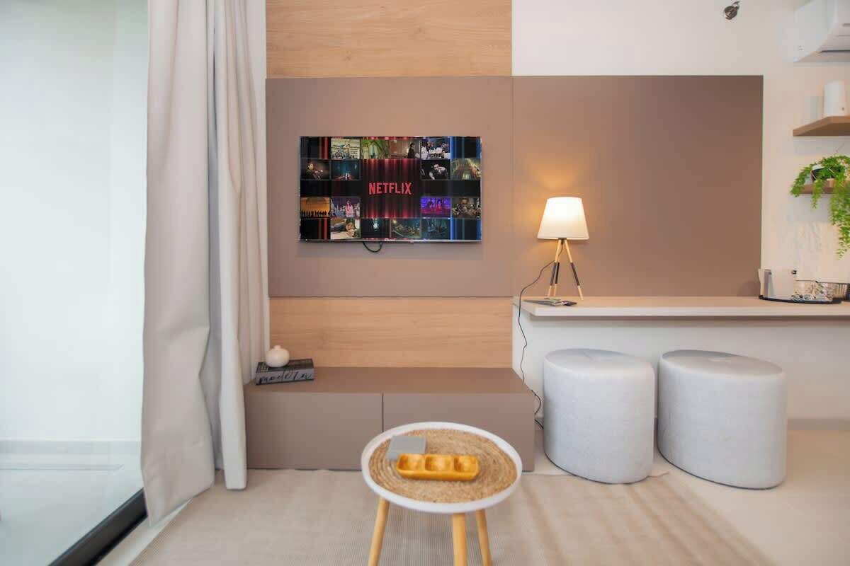Une chambre d’hôtel moderne avec une décoration murale inspirée de Netflix, une petite table ronde avec un plateau, et deux poufs.