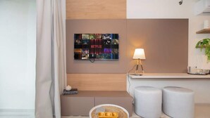 Una camera d'albergo moderna con un quadro raffigurante Netflix, un piccolo tavolino con vassoio e due poggiapiedi.