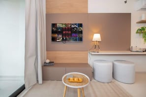 Ein modernes Hotelzimmer mit Wandbildern von Netflix, einem kleinen runden Tisch mit Tablett und zwei Hocker.