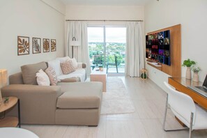 Ein modernes Wohnzimmer mit Sofa, Couchtisch, TV-Wand und einem Balkon mit Aussicht.
