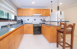 Una cocina moderna con armarios de madera, horno empotrado, microondas y refrigerador.
