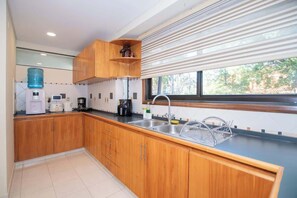 A modern kitchen with wooden cabinets, a built-in sink, and a large window. - Spacious Mburucuyá Duplex | Pool, BBQ & Jacuzzi (Asunción)