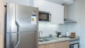 Une cuisine moderne équipée d’un réfrigérateur en acier inoxydable, d’un four à micro-ondes, d’un évier et de meubles de rangement en bois.