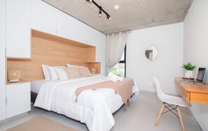 Une chambre moderne avec une tête de lit en bois, un bureau avec un ordinateur portable et une chaise blanche.