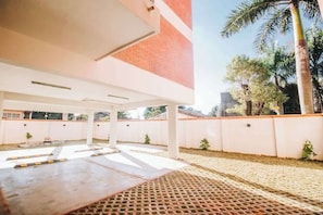Un espace extérieur abrité, doté d’un mur en briques, de palmiers et d’un sol à motifs.