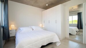 A bedroom with a bed, nightstands, a wardrobe, and a mirror.