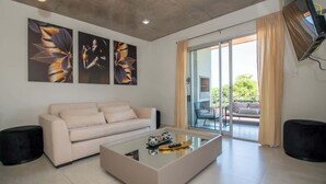 A modern living room with a sofa, a glass coffee table, and artwork on the wall.