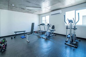 A gym with exercise equipment, a bench, and a window.