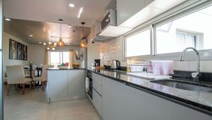 A modern kitchen with a central island, stainless steel appliances, and pendant lighting.