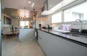 Una cocina moderna con una isla central, electrodomésticos de acero inoxidable e iluminación colgante.