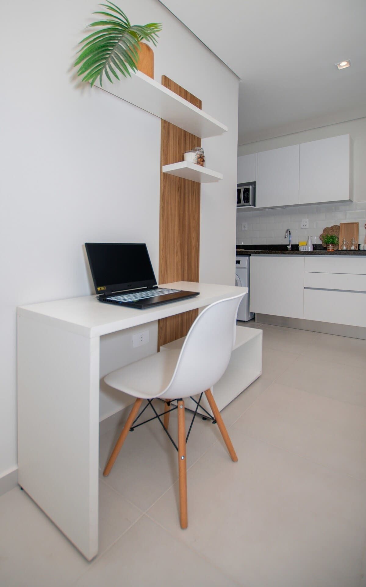 Una cocina moderna con armarios blancos, microondas integrado y una encimera con cafetera.