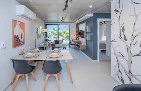 A modern dining area with a table set for two, a ceiling-mounted air conditioner, and a view of the outdoors. - Apartment Near Malls with Pool, Gym, Cinema&WiFi (Asunción)