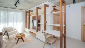 Een moderne woonkamer met een bank, een eettafel, een stoel en ingebouwde houten planken.