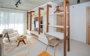 Uma sala de estar moderna com um sofá, uma mesa de jantar, uma cadeira e estantes de madeira embutidas.