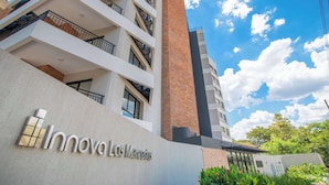 Um edifício de vários andares com varandas, uma chaminé de tijolos bem visível e uma placa com a inscrição 'Innoval Los Mercedes'.