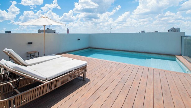 Piscina no terraço com espreguiçadeiras e deck de madeira.