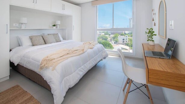 Un dormitorio moderno con cama, escritorio y un amplio ventanal.