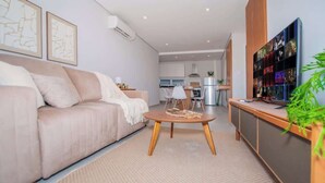 Una sala de estar moderna con un sofá, una mesa de centro y un televisor montado en la pared.