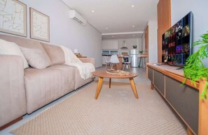 Una sala de estar moderna con un sofá, una mesa de centro y un televisor montado en la pared.