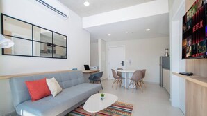 A modern living room with a sofa, a coffee table, and a dining area with chairs.
