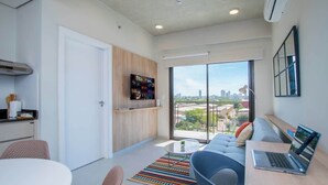 A modern apartment with a kitchen, dining area, and a large window with a city view.