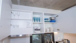 Una cucina con mobili bianchi, una cappa in acciaio inossidabile e un frigorifero con sportello in vetro.