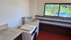 A laundry room with a washing machine, dryer, and a window with a view of the outside. - Aremiti - Fare Orotia (Avera, Raiatea)