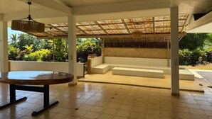 An indoor area with a round table, a bench, and a thatched roof structure. - Aremiti - Fare Orotia (Avera, Raiatea)