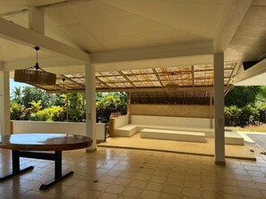 An indoor area with a round table, a bench, and a thatched roof structure. - Aremiti - Fare Orotia (Avera, Raiatea)
