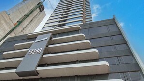 Un edificio de gran altura con un llamativo letrero 'Petra Towers', amplias ventanas y un diseño arquitectónico moderno.