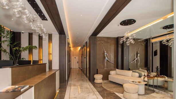Un moderno vestíbulo de hotel con una recepción, zona de estar y elementos decorativos.