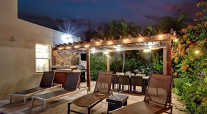 Eine Terrasse im Freien mit Liegestühlen, einem Grill und Lichterketten.