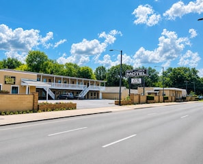 A motel with a signboard, a parking lot, and a clear sky.