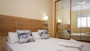 A hotel room with a bed, a wooden headboard, a mirror, and a bedside table with a lamp. - Ref: 258. Charming attic apartment in Los Boliches close to the beach (Fuengirola)