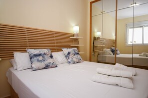 Ein Hotelzimmer mit Bett, Holz-Kopfteil, Spiegel und Nachttisch mit Lampe.