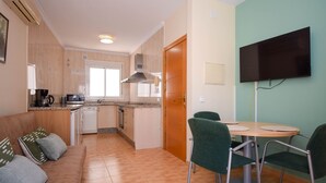 A compact kitchen with a dishwasher, microwave, and coffee maker. There is a dining area with a table and chairs, and a TV mounted on the wall. - Ref: 258. Charming attic apartment in Los Boliches close to the beach (Fuengirola)