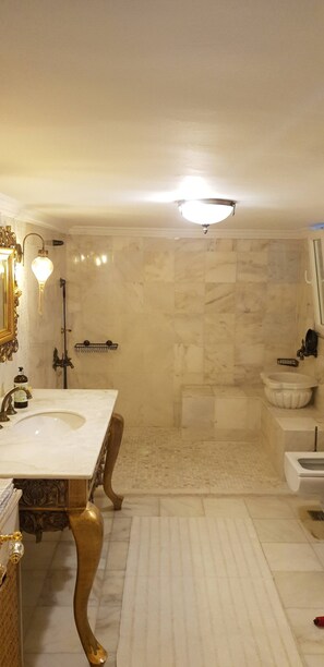 Ein Badezimmer mit einem großen Marmorwaschbecken, einer separaten Duschkabine und einer Toilette.